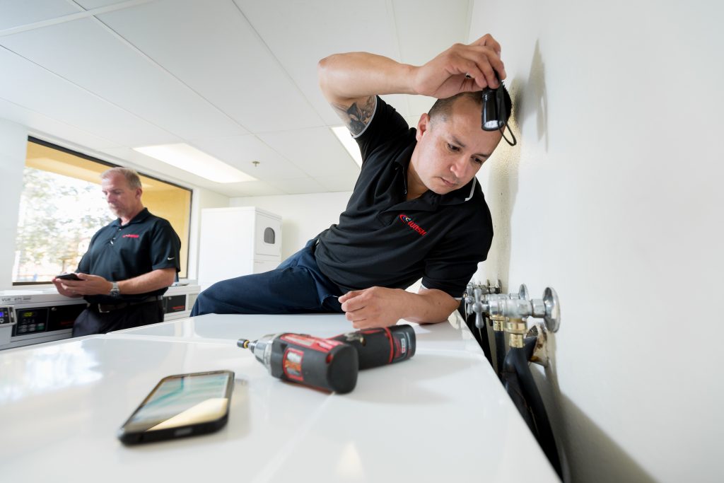 Richie Kay, service manager, and Danny Sanchez, lead technician for WASH Multifamily Laundry, on a service call.