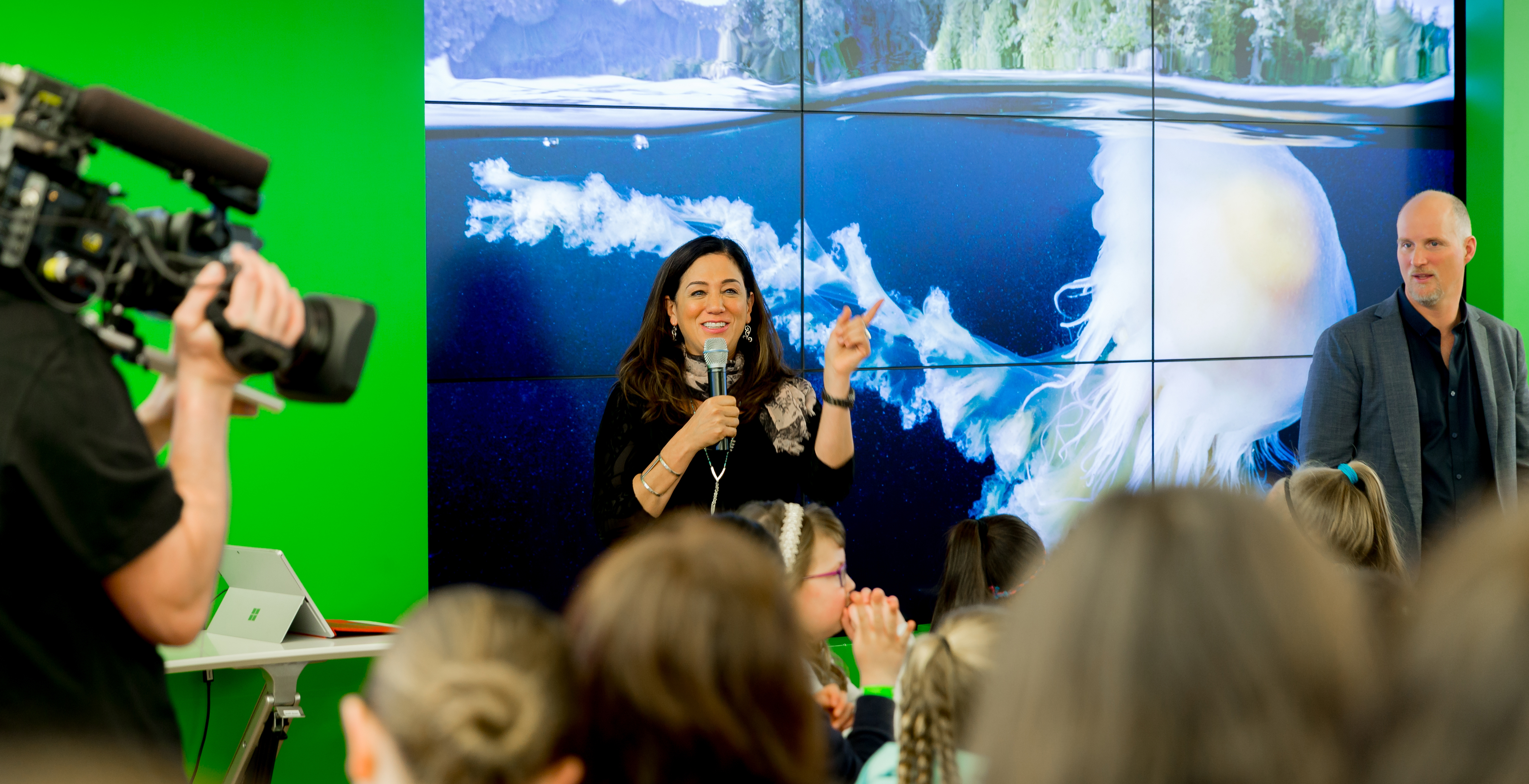 Photo of smiling woman speaking to crowd of girls at Microsoft store