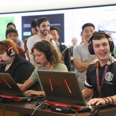 young men wearing headsets sit in front of laptops