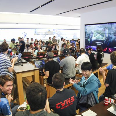 A full room of gamers gather around tables