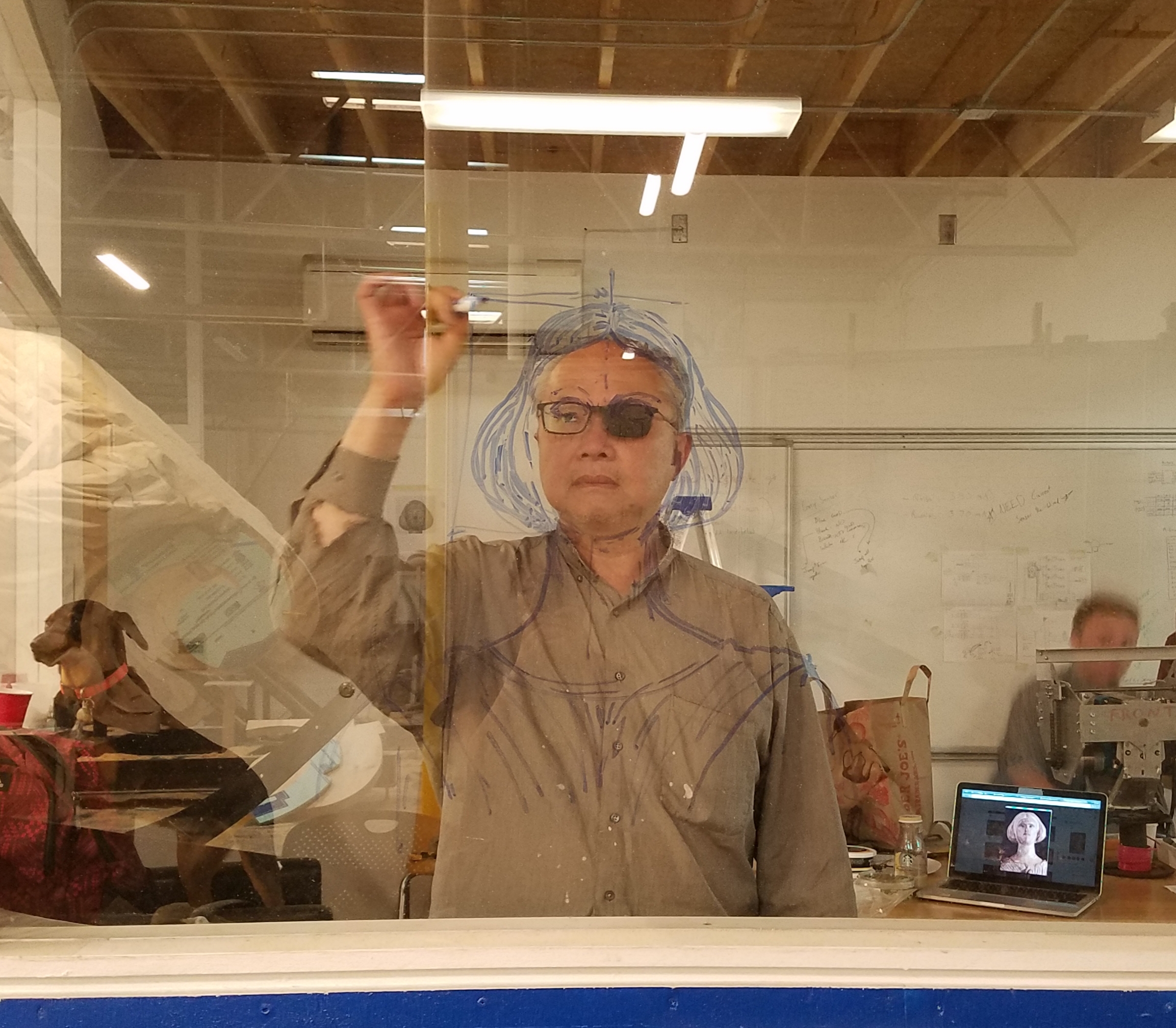 Artist Mel Chin, standing behind a clear window, sketches a drawing of Jenny Lind