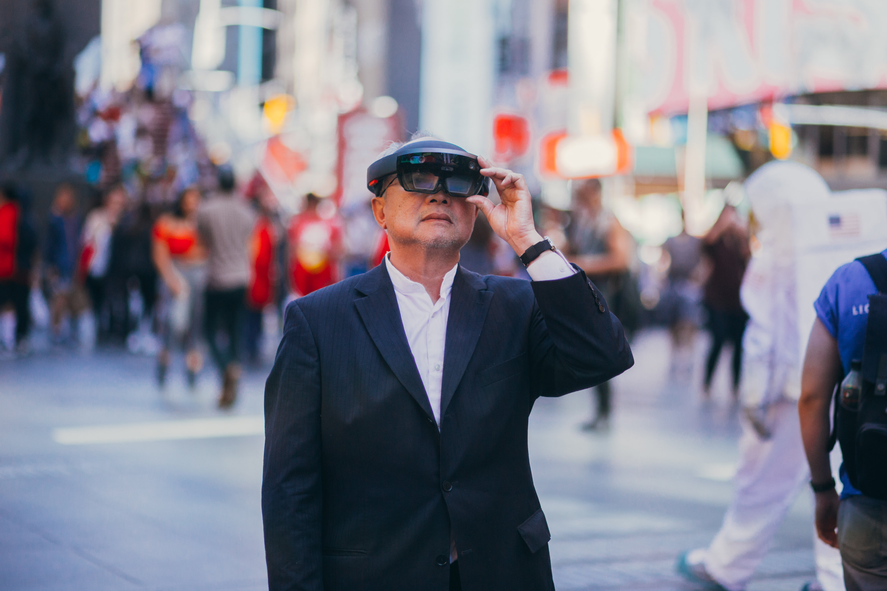 Artist Mel Chin, dressed in a suit, tries on the Microsoft HoloLens in Times Square