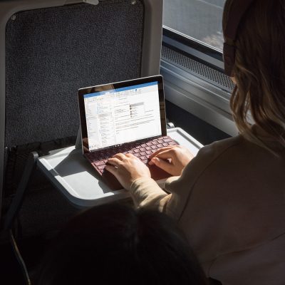 A woman uses a Surface Go on a train