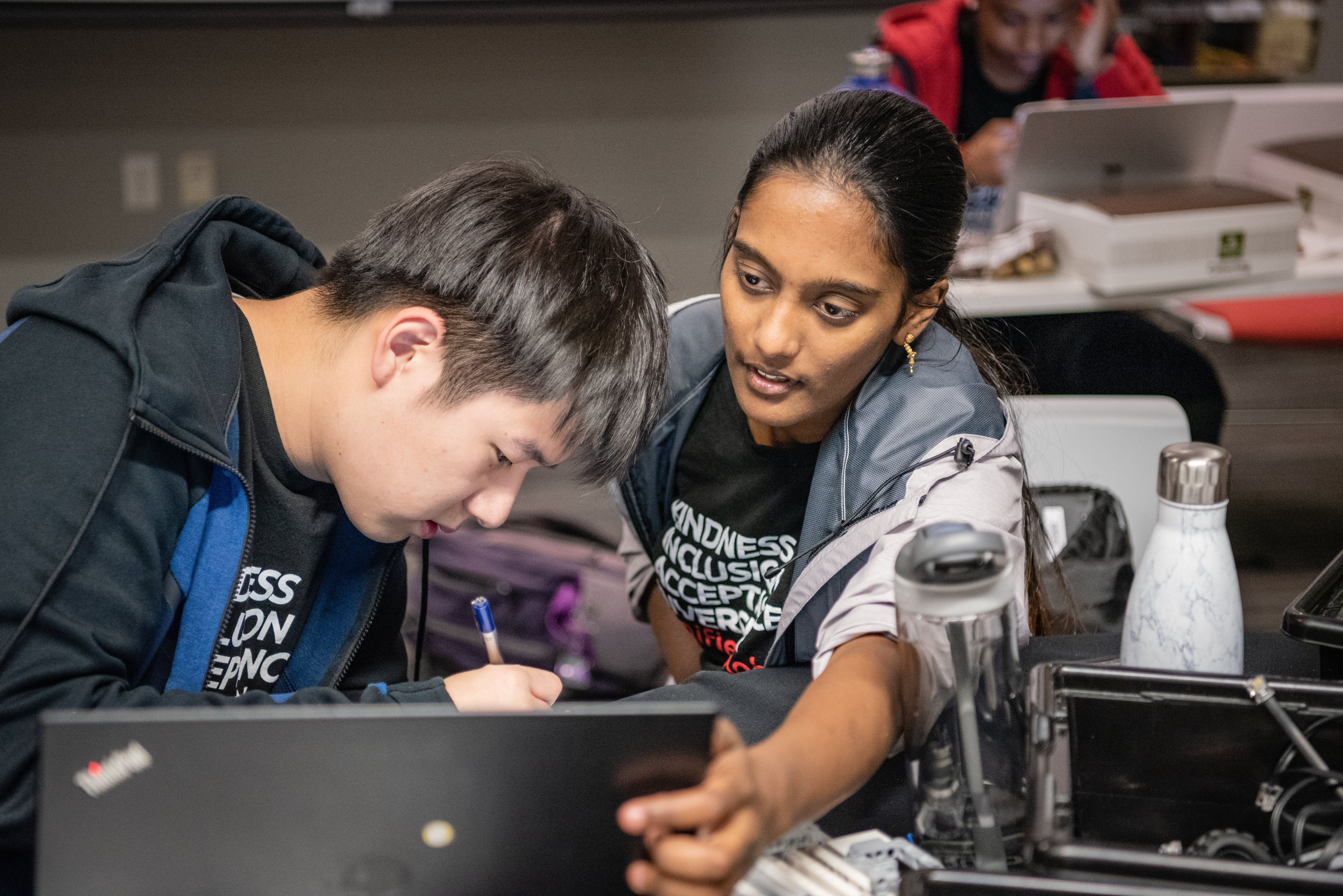 Photo of boy and girl sitting in front of a computer, working on building a robot.