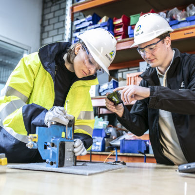 a man and a woman work on a piece of equipment