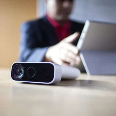 a man works on a surface device with an azure kinect in the foreground