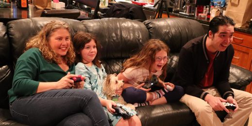 Family of four playing video games together on their couch