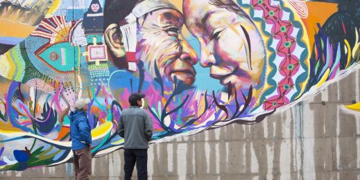 Two people look up at an Inuit mural