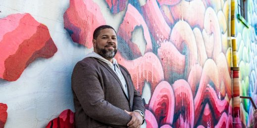 Man stands in front of colorful mural