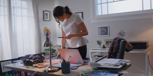 Woman working at home with a phone and a laptop computer