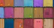 Man wearing a hardhat walking past stacks of shipping containers