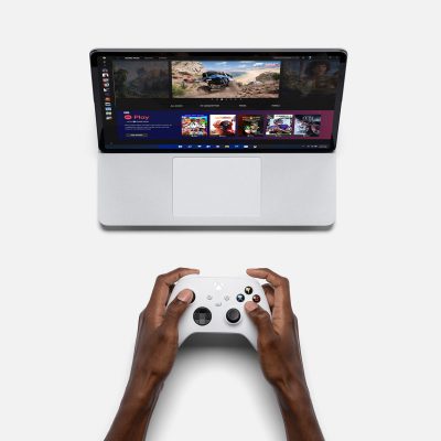 A person playing a game on a Surface laptop using a Xbox controller