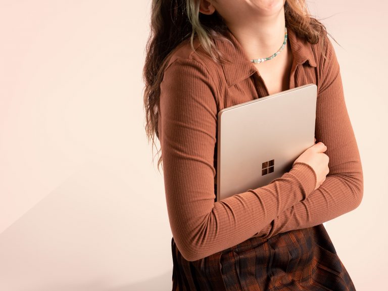 Woman holding Surface Laptop Go 2 in Sandstone