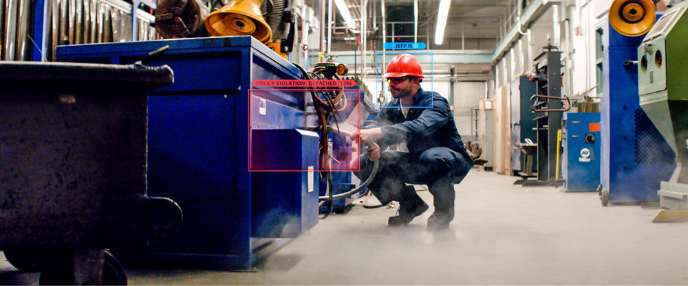 Man wearing a helmet squatting near a blue machine