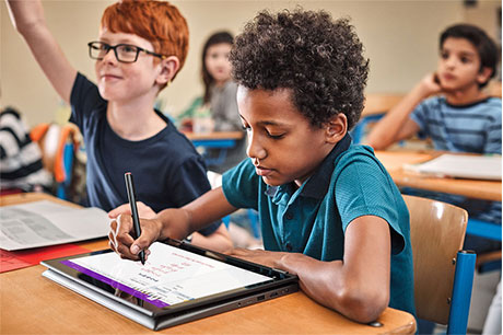 Young boy doing mathematics on a laptop in a classroom setting. 