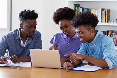 Three students collaborating on a project in a library setting