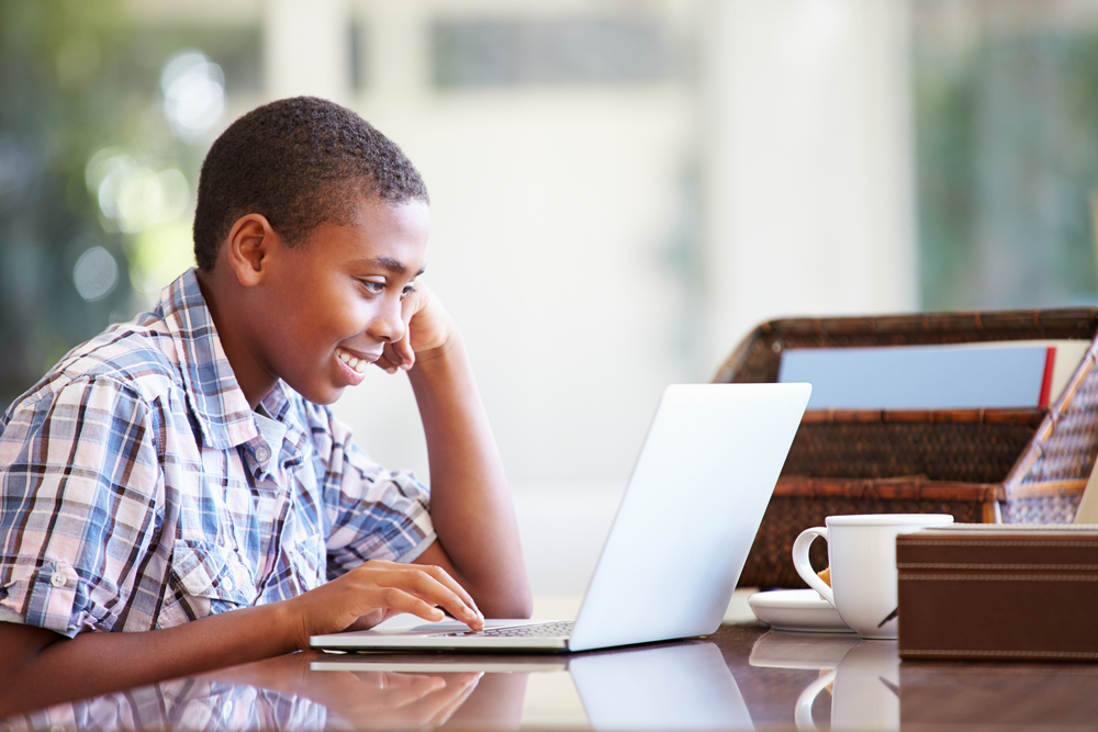 Young primary school boy participating in an online classroom session via his laptop.