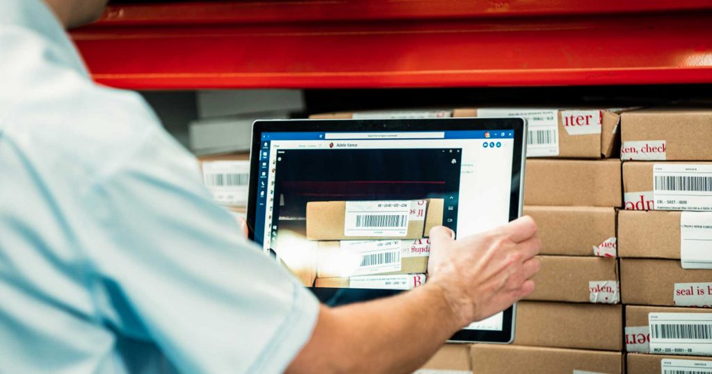 Employee uses a tablet to scan in product barcodes of company stock