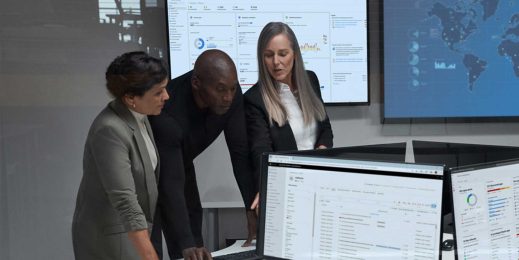 Three security professionals standing at a computer monitor.