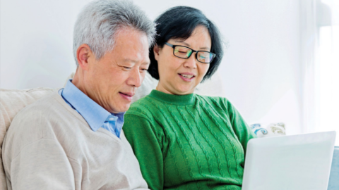 an elderly couple shares a laptop