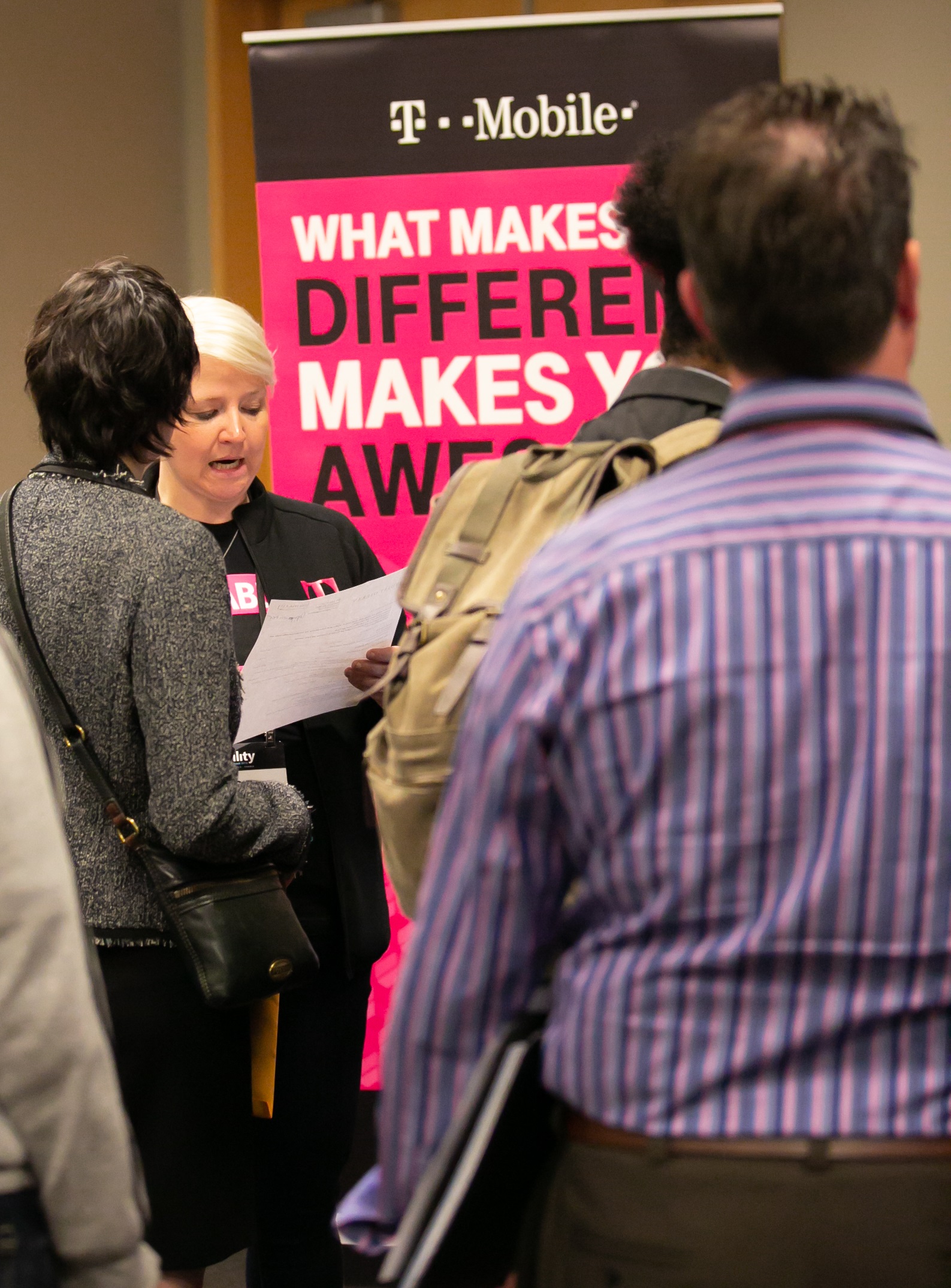 Photo of people standing in front of a T Mobile sign that says What Makes You Different Makes You Awesome