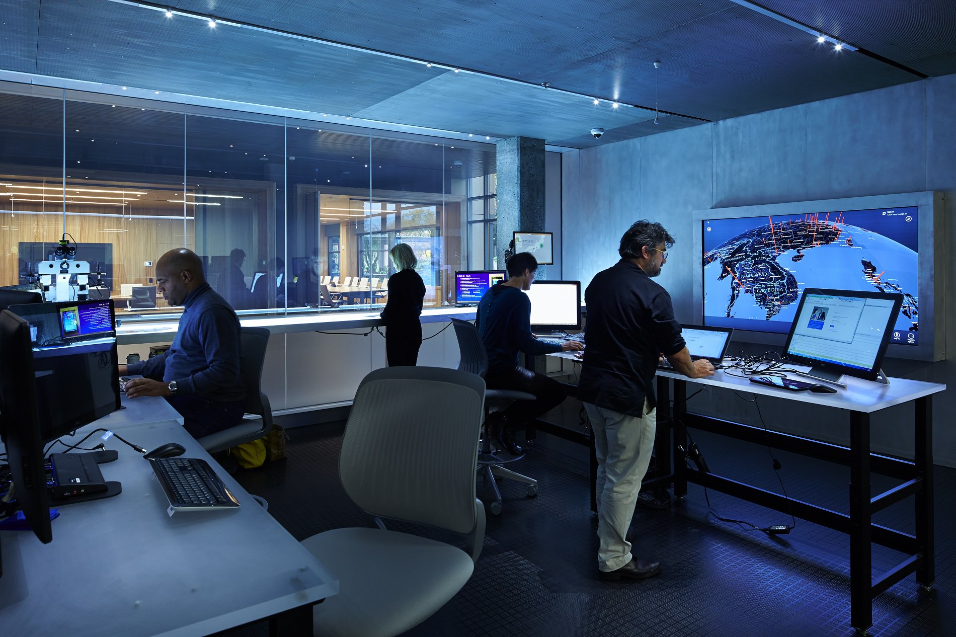 Photo of people working in front of computer screens with maps of the world