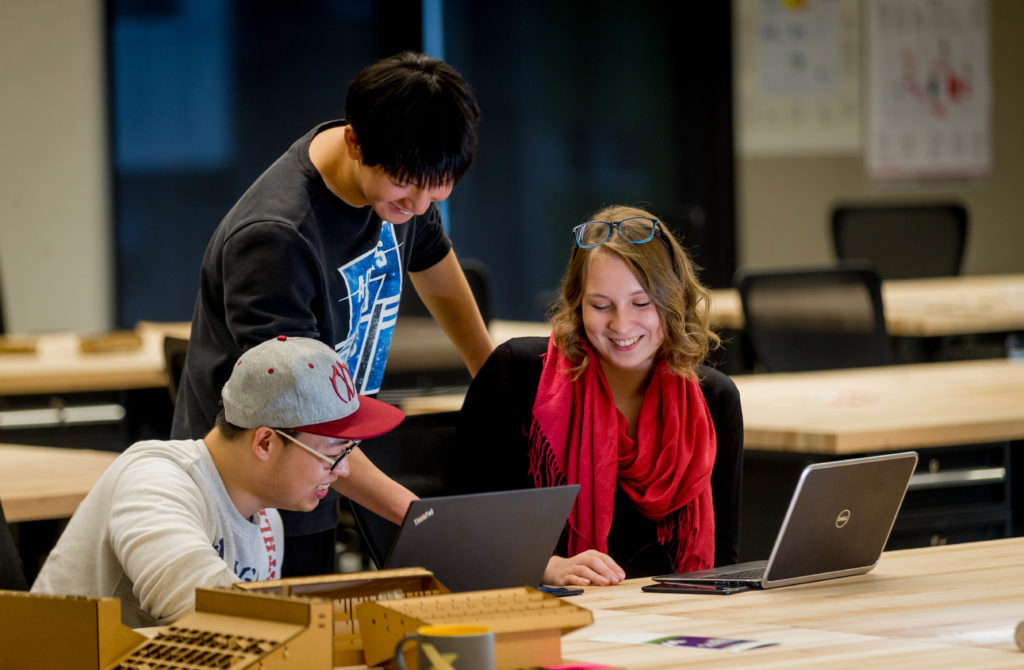 a team of students sit around a laptop