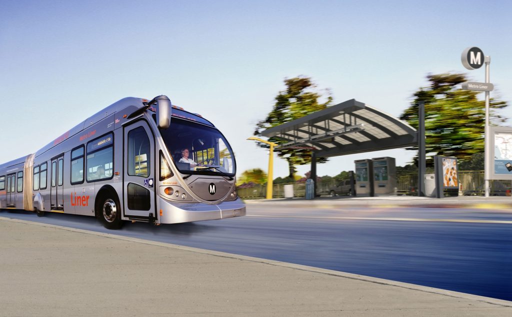 Silver bus moves near bus stop