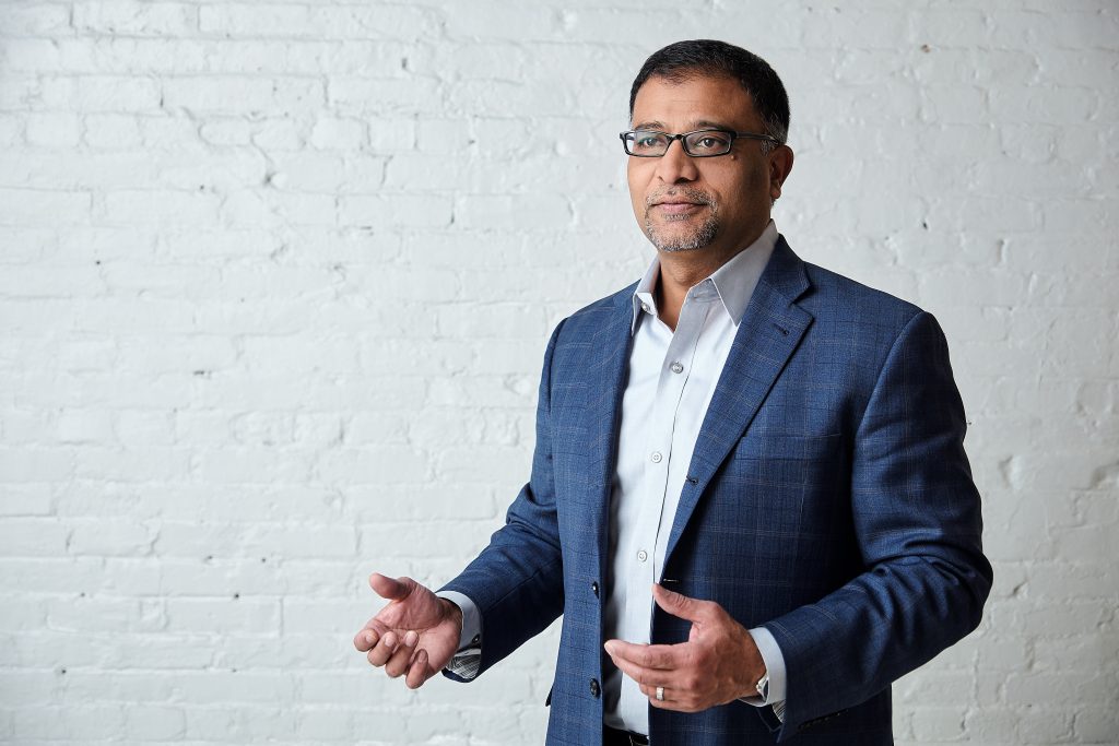 Prakash Venkata stands next to a brick wall.