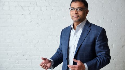 Prakash Venkata stands next to a brick wall.