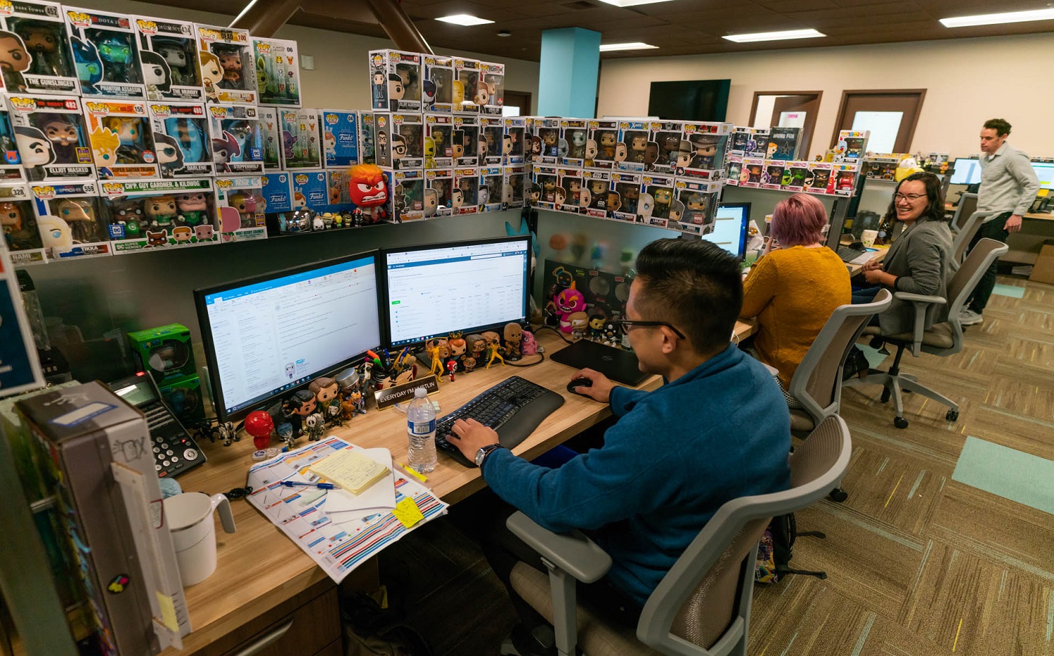 An employee's desk is surrounded by a wall of Funko toys