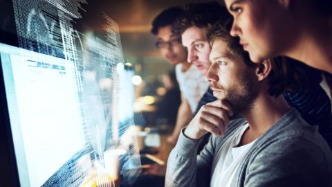 A group of programmers work on computer code.