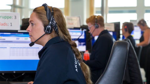 Photo of workers wearing headsets and sitting in front of computers at Emergency Medical Services Copenhagen.