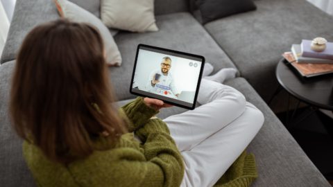 A woman speaks with her doctor via a digital tablet