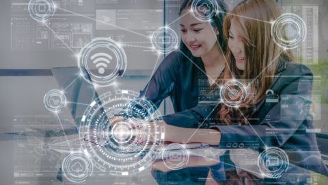 Two young women collaborate on a laptop.