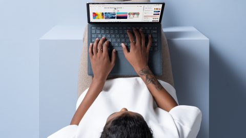 A woman sits with a laptop on her lap