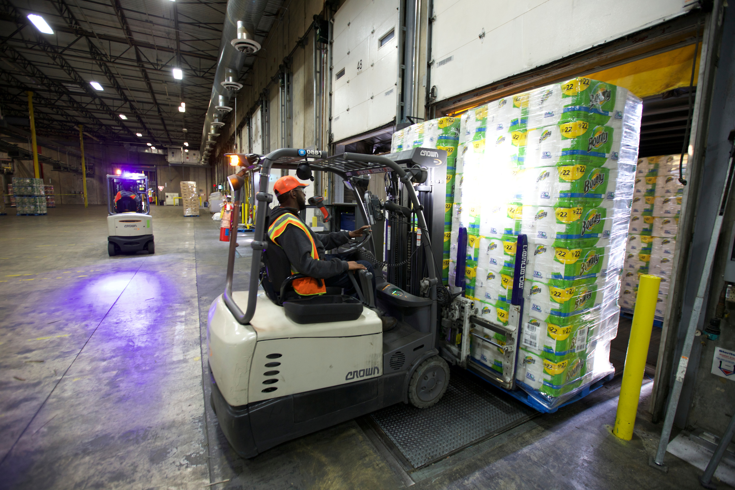 A man operates a fork lift loaded with Bounty paper towels.