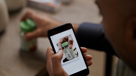 Detail photo of a man's hand holding a phone and using the Seeing AI app