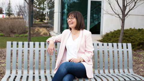 woman sitting on bench in front of wooded area laughing