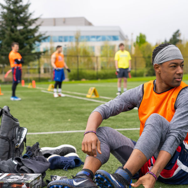 A photo of a man wearing athletic gear sitting on the sidelines of a football field