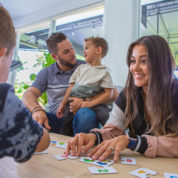 A woman smiles at her son while they play a puzzle