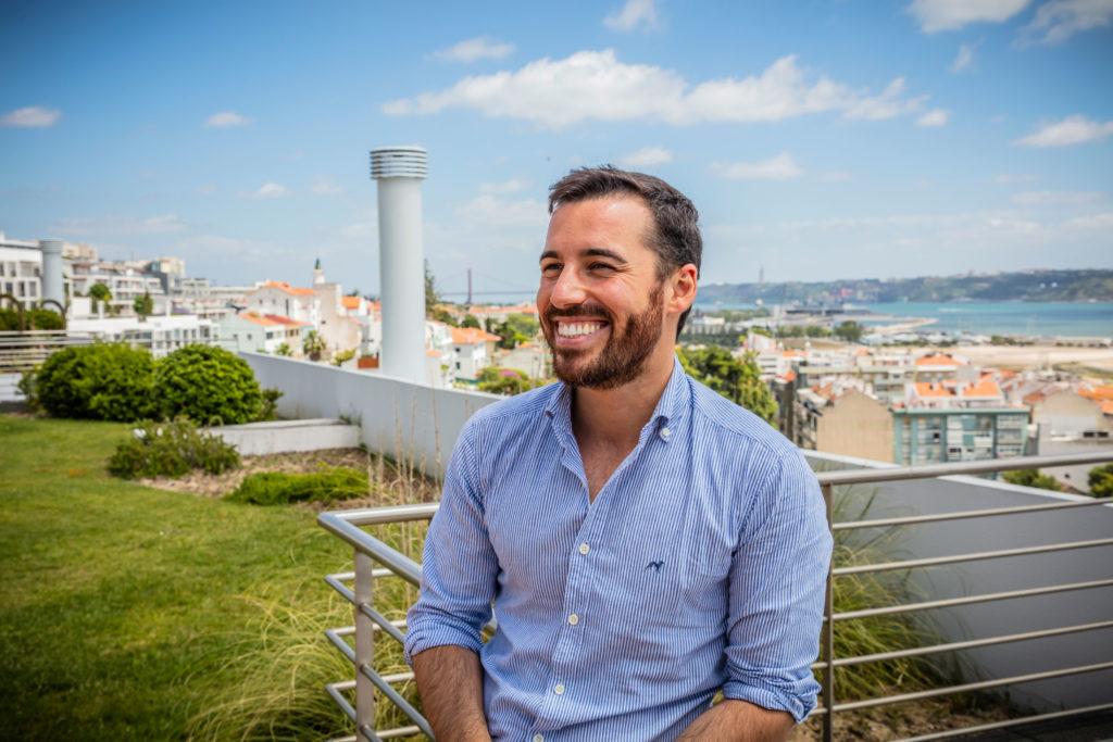 a man smiling with the ocean behind him