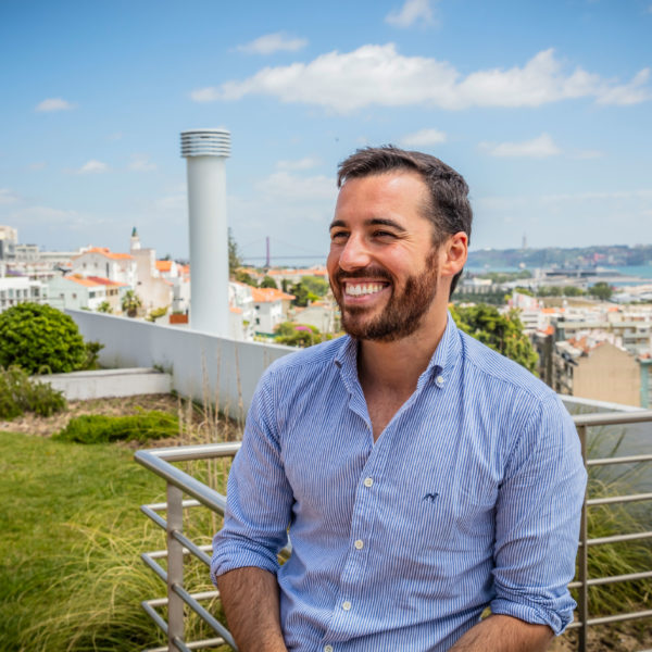 a man smiling with the ocean behind him