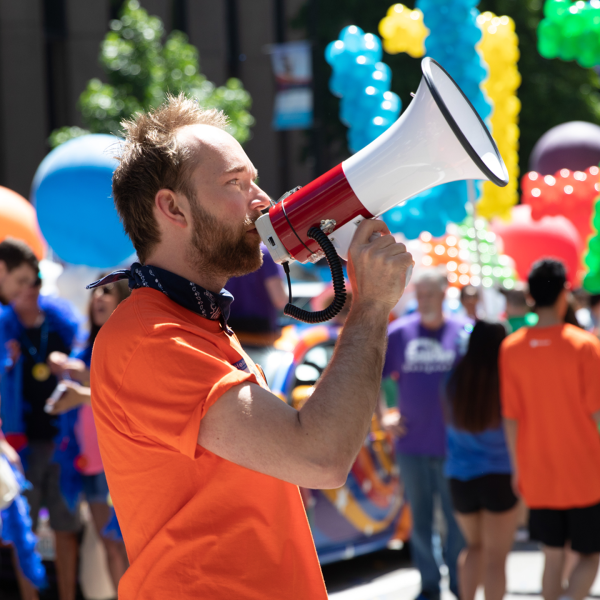 Aleksey speaking into a megaphone at a Pride rally.