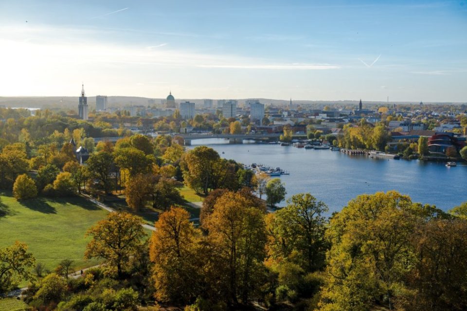 Landschaftsaufnahme, Wiese mit Bäumen und einem Fluss in der Nähe der Stadt