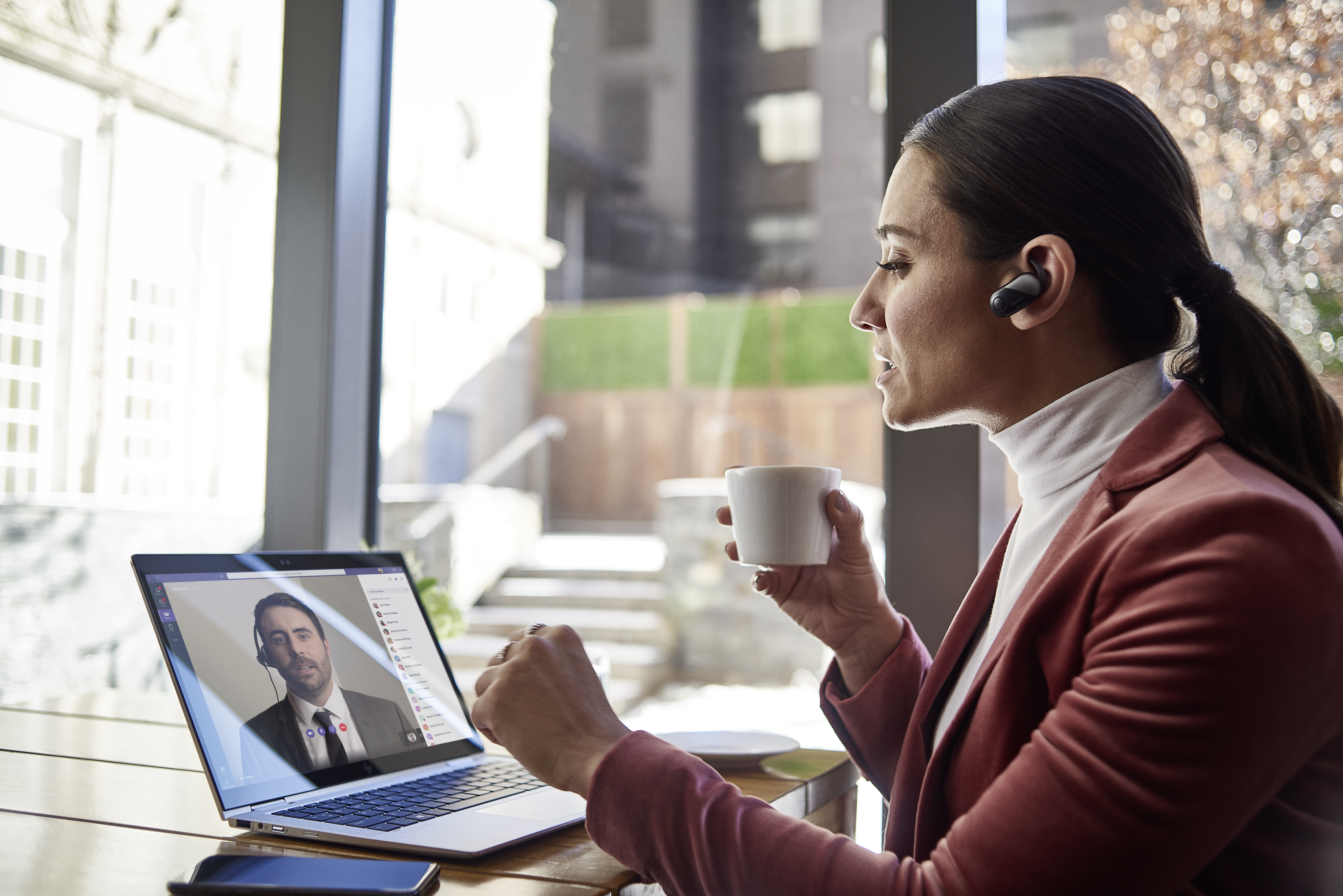 Frau sitzt an Schreibtisch und nutzt Teams auf ihrem Laptop