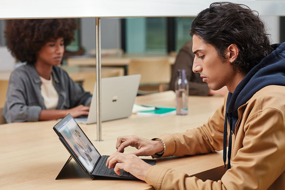 Schülerin und Schüler arbeiten in der Schulbibliothek an Surface Devices