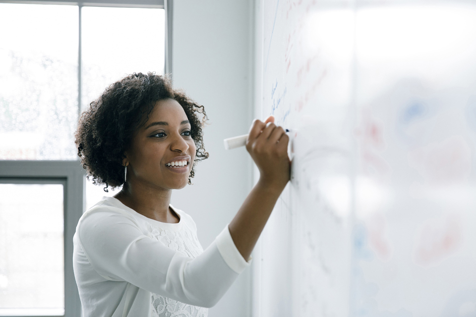 Frau schreibt an ein Whiteboard