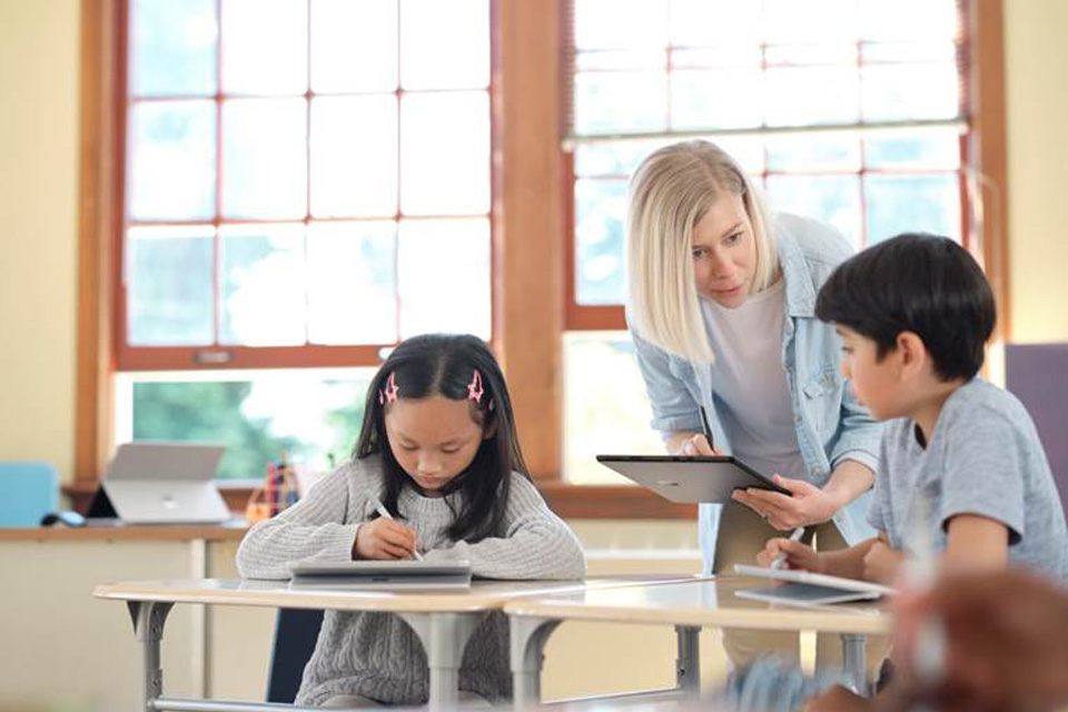 Lehrerin mit Tablet spricht mit Kindern