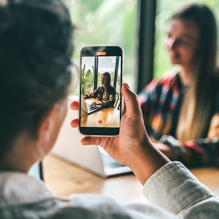 Mann macht mit einem Smartphone ein Bild von einer Frau